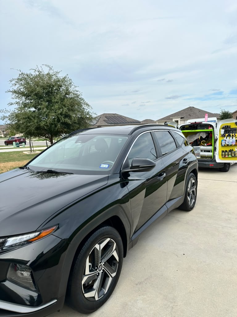 Black SUV in a driveway with the mobile detailing van behind it